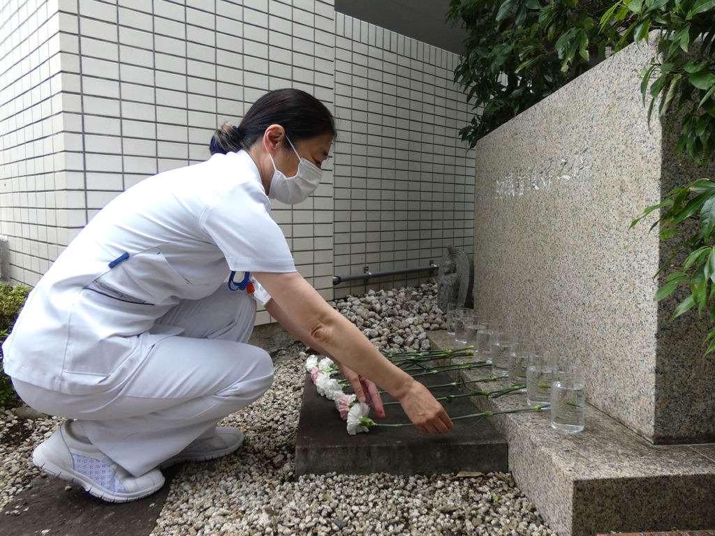 慰霊碑に花を手向ける看護師＝静岡市葵区の市立静岡病院