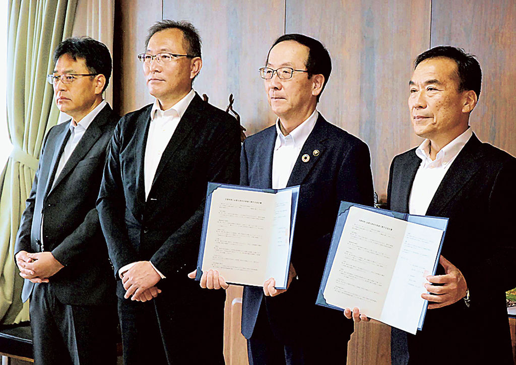 資材の調達に関する協定を締結した秋元社長（右）と小長井市長（右から２人目）ら＝富士市役所