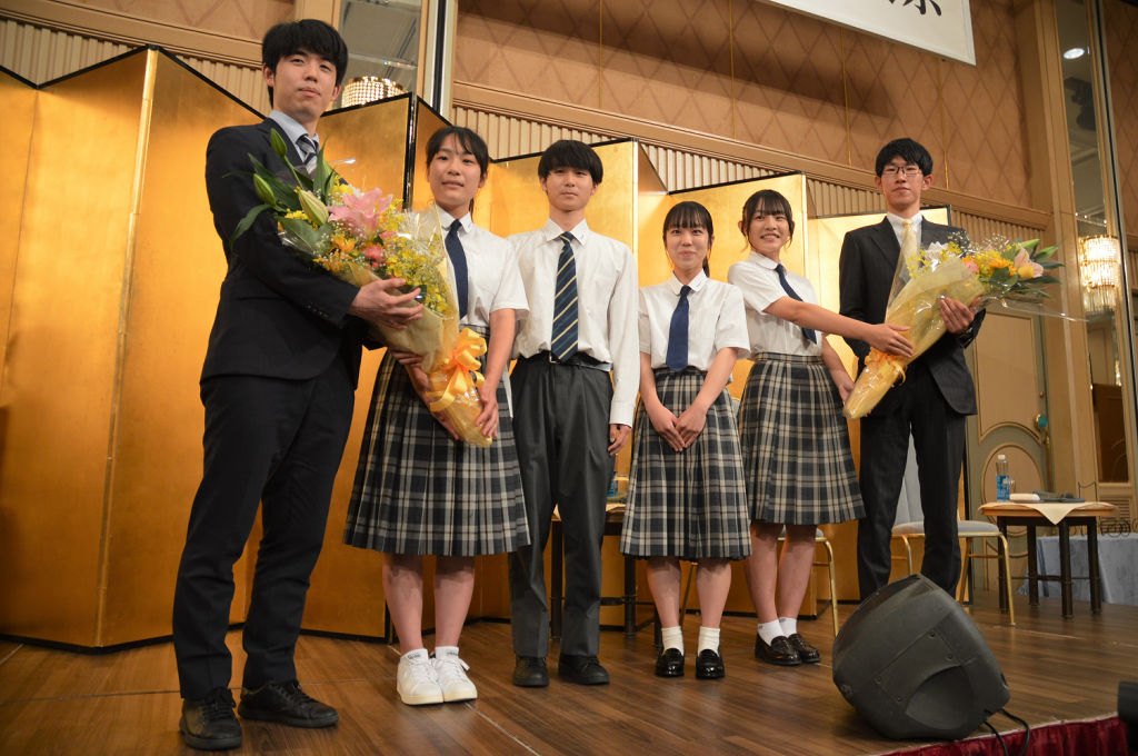 藤井聡太棋聖（左）と佐々木大地七段（右）に花束を手渡した沼津市立高の生徒＝２日夜、沼津市内