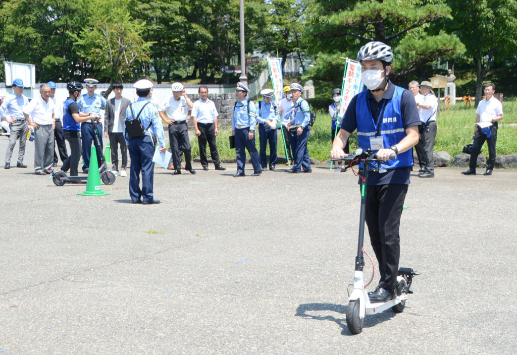 電動キックボードを乗車体験する関係者＝１１日午前、静岡市葵区の駿府城公園