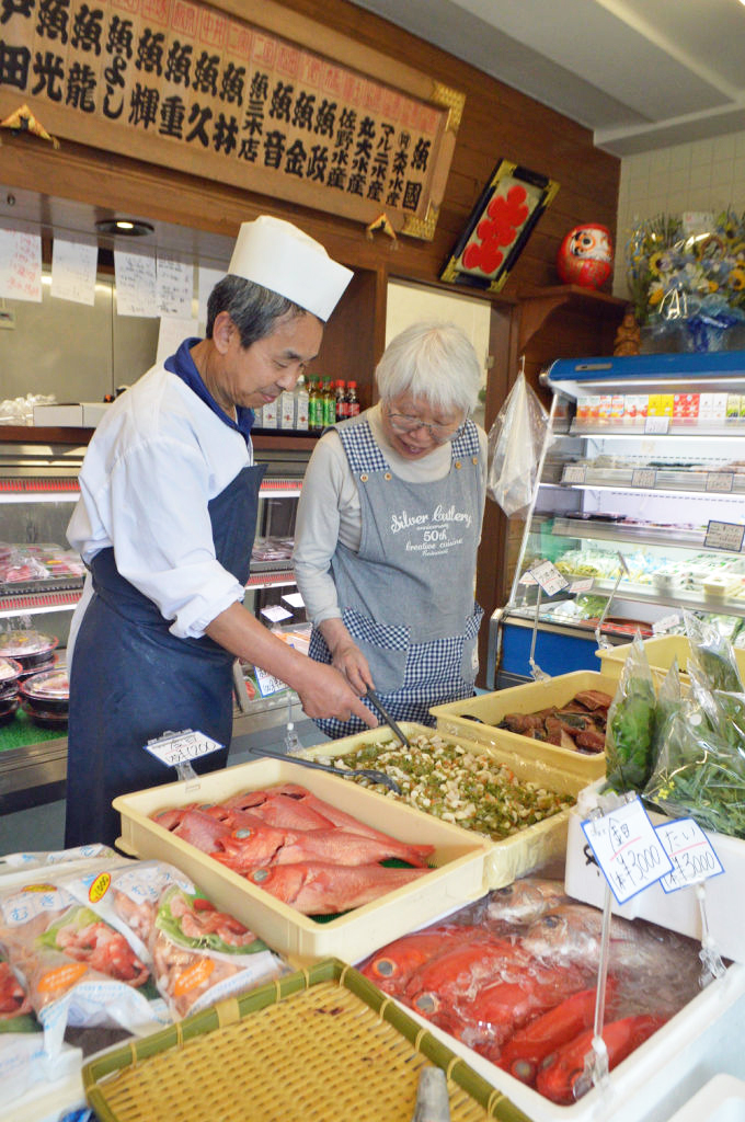 買い物客に商品を紹介する高橋照幸さん（左）＝熱海市伊豆山の魚久