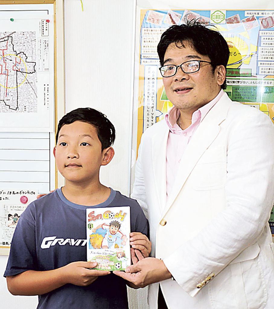 ジャン君（左）に漫画を手渡すユーン理事長＝浜松市中区の相生小