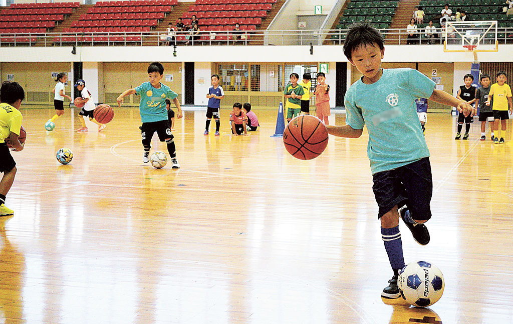 サッカーボールとバスケットボールをドリブルする児童＝静岡市葵区の市中央体育館（写真の一部を加工しています）
