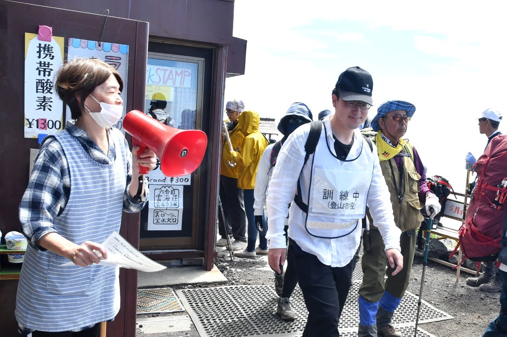 訓練参加者に下山を呼びかける山小屋の従業員（左）＝１９日午前１０時１５分ごろ、富士山富士宮口６合目