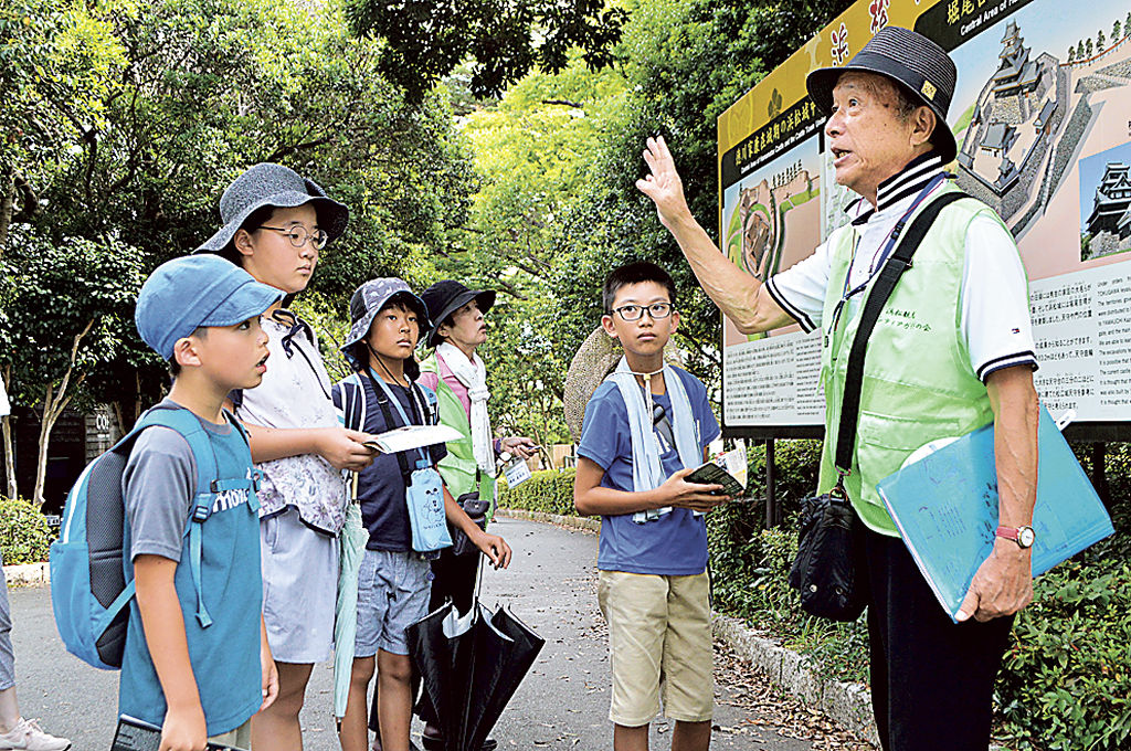 ガイド（右）から浜松城の歴史について説明を受ける児童＝浜松市中区の浜松城公園