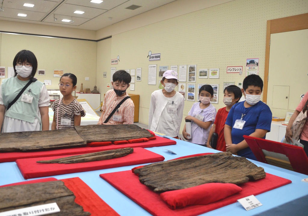 舟の部材を間近で見学する児童たち＝磐田市見付の中央図書館（画像の一部を加工しています）