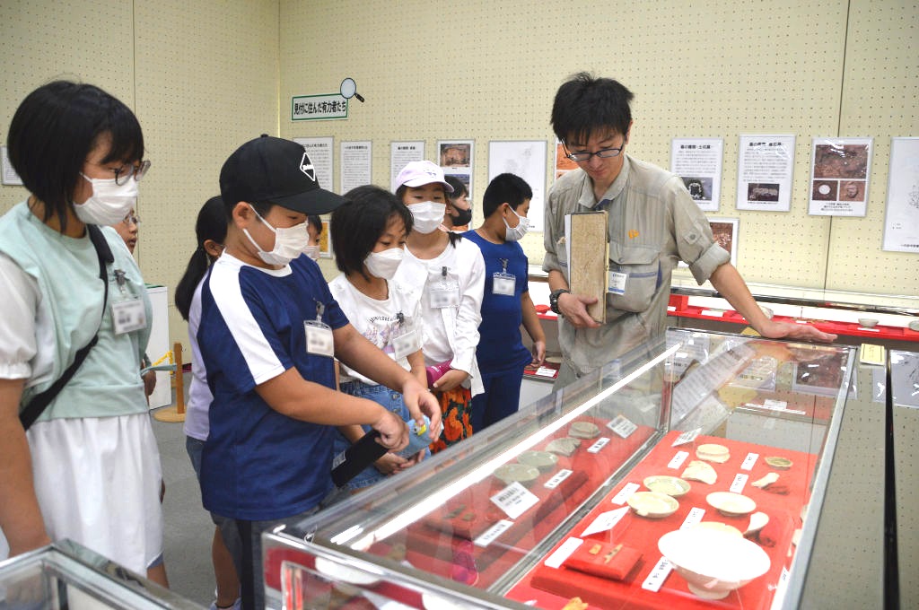 発掘調査などで出土した品々を見学する児童たち＝磐田市見付の中央図書館（画像の一部を加工しています）