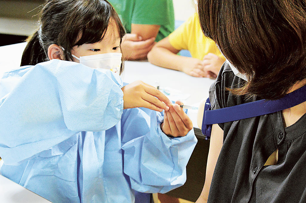 医者になりきりワクチン接種を模擬体験する子ども＝浜松市中区の浜松こども館