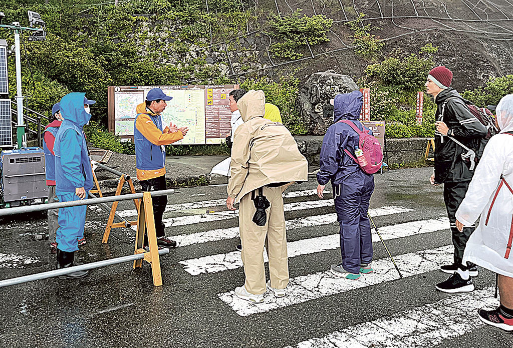 外国人に引き返すよう求める富士登山ナビゲーター（左側）＝１４日午後４時ごろ、富士山富士宮口５合目