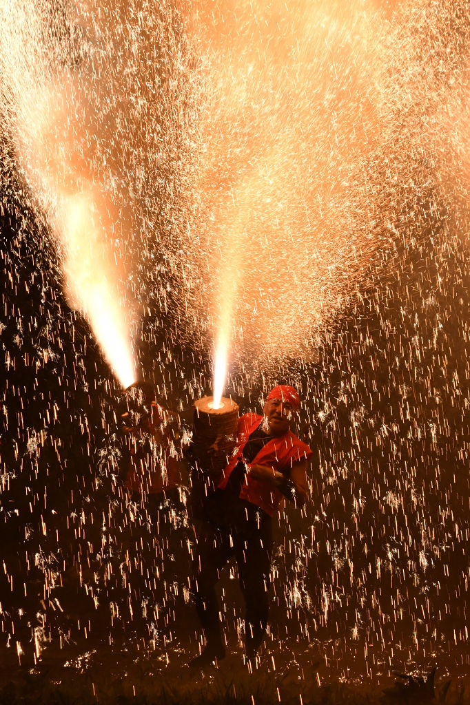 火の粉を浴びながら手筒花火を掲げる保存会＝富士宮市原