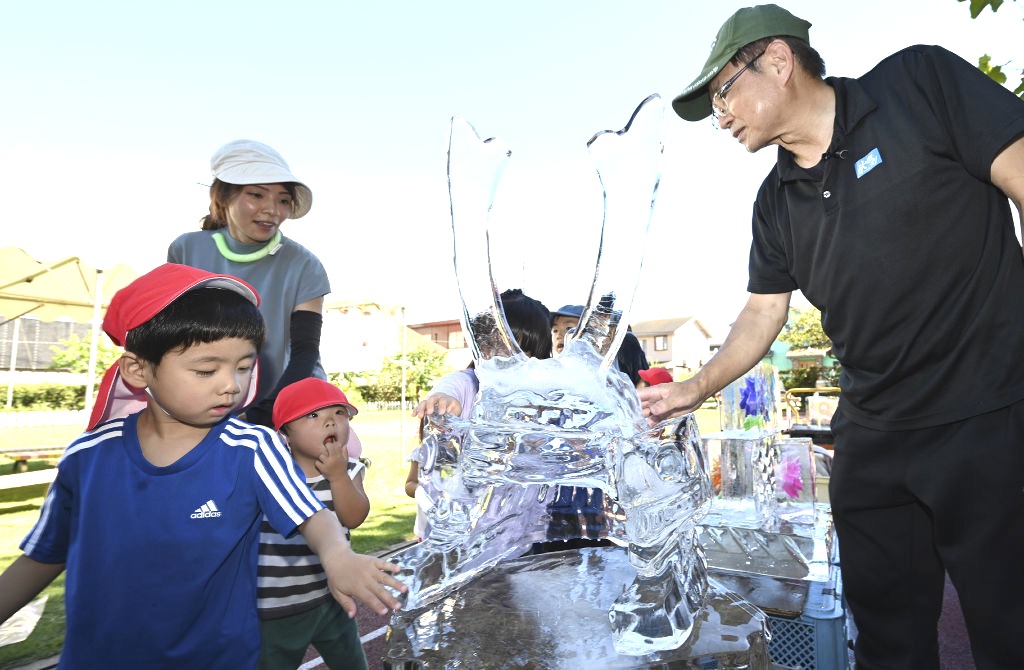 二橋さん（右）が披露した氷のかぶとに触れる子どもたち＝浜松市南区の浜松こども園
