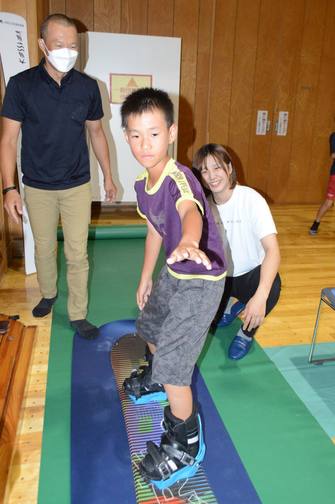 子どものスノーボード体験を見守る三木選手（右）＝掛川市大池の市総合体育館さんりーな