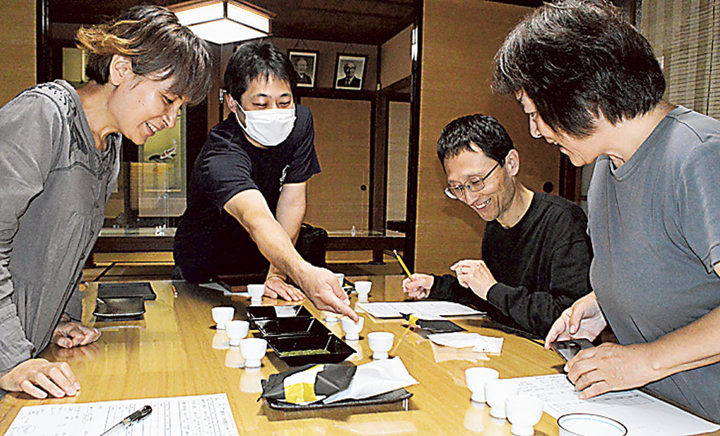 小泉純也さん（左から２人目）の説明を受け、茶の魅力を学ぶ参加者＝藤枝市茶町の真茶園