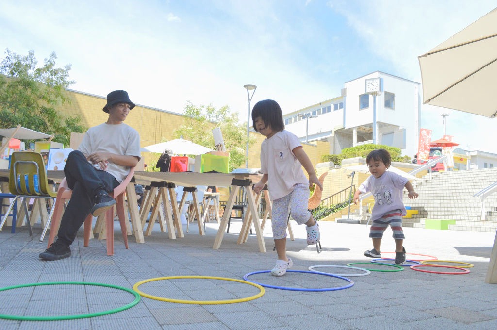 フラフープで遊ぶ子ども＝２日、長泉町のＪＲ下土狩駅前のコミュニティながいずみ北口広場