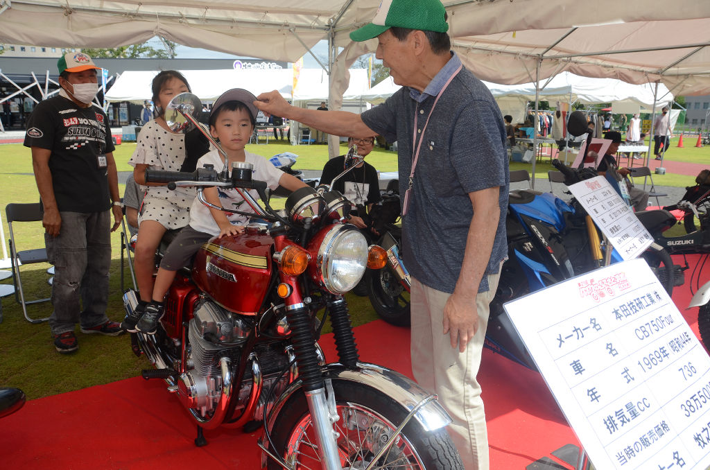 展示バイクに乗せてもらう子ども＝浜松市中区の浜松出世パーク葵広場
