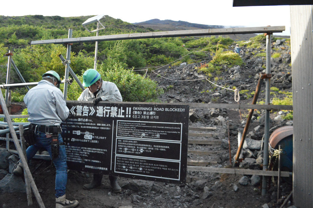 通行禁止の看板を設置する関係者＝１０日午後５時ごろ、富士山富士宮口６合目