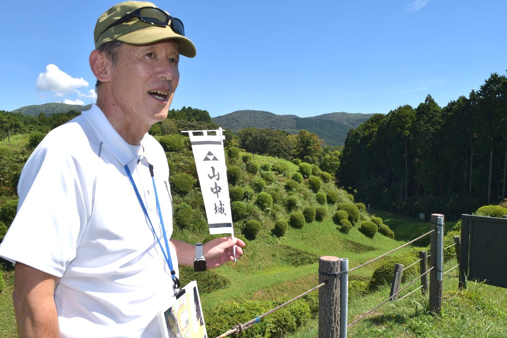 「障子堀」をはじめ、城の魅力を伝えるガイドを始める芦川さん＝三島市の山中城跡