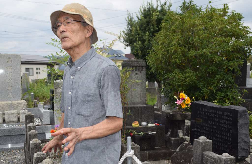 大杉栄の墓前で思いを語るおいの大杉豊さん＝１６日午前、静岡市葵区の沓谷霊園