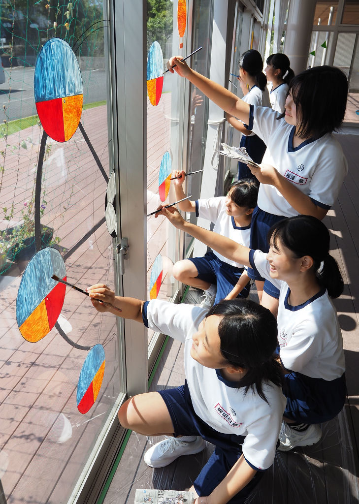 ガラス窓に観覧車などのイラストを描く生徒たち＝磐田市高見丘の豊田東交流センター（写真の一部を加工しています）