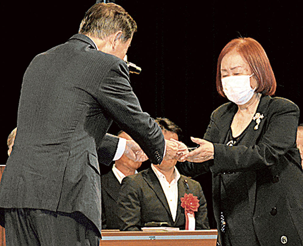 北村藤枝市長（左）から代表して祝い金を受け取る鈴木さん＝市民会館