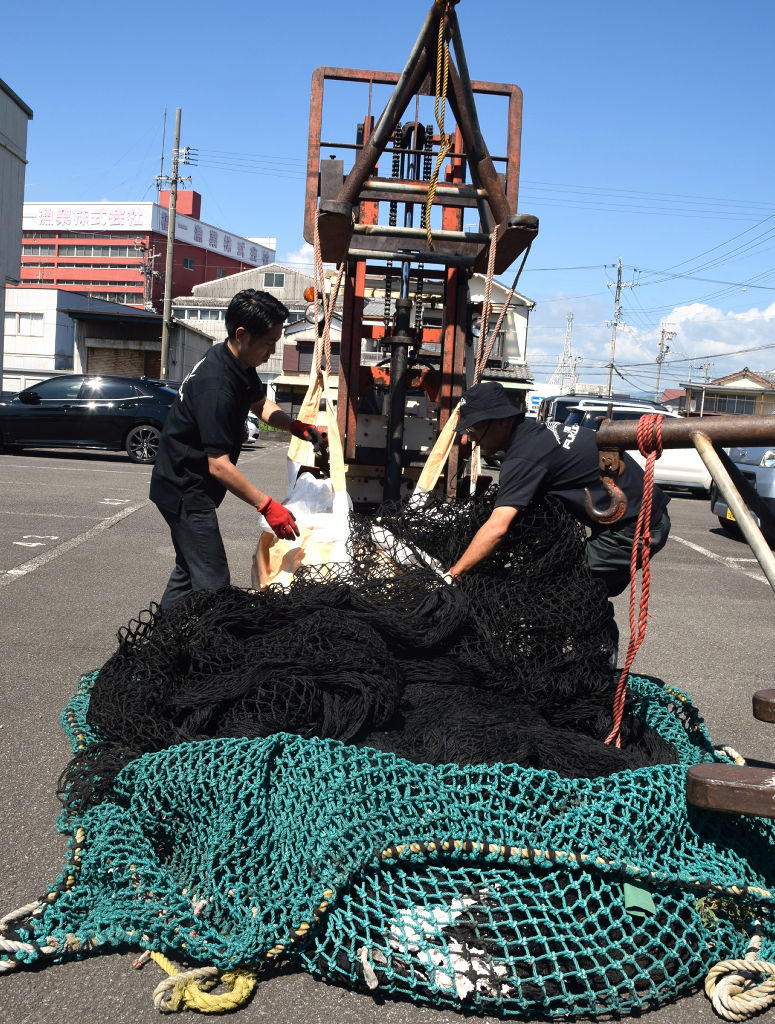 使われなくなった漁網をリサイクルのために選別する関係者＝焼津市中港