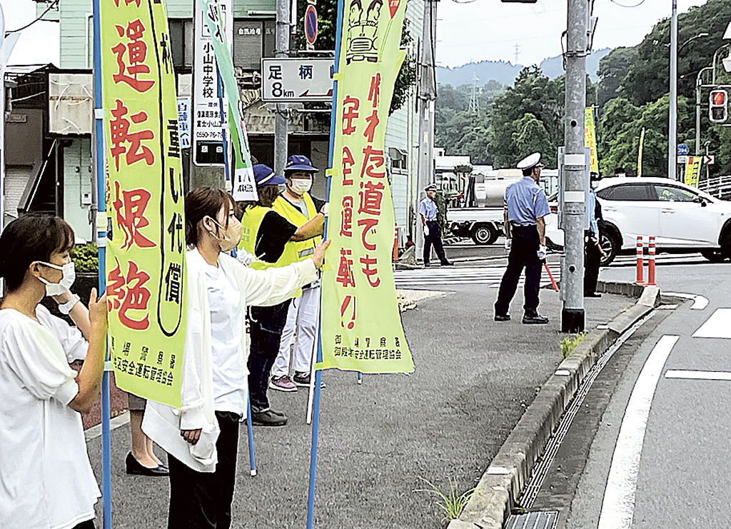 のぼり旗を手に交通安全の呼びかけを行う参加者たち＝小山町役場前