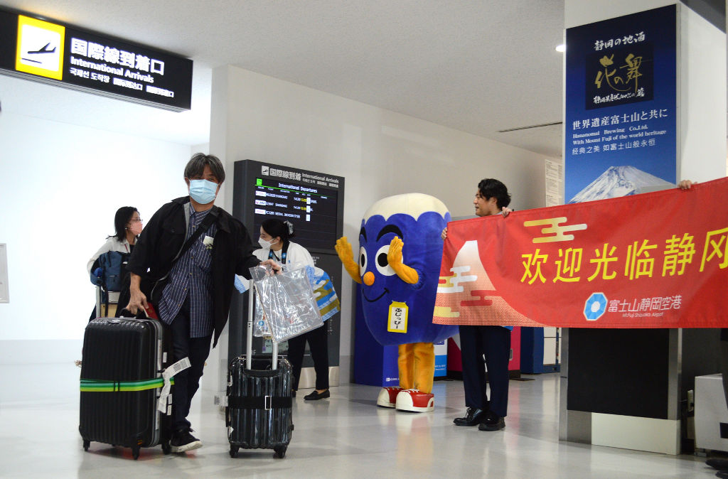 国際線到着口で空港関係者から歓迎を受ける乗客ら＝２４日午後、静岡空港