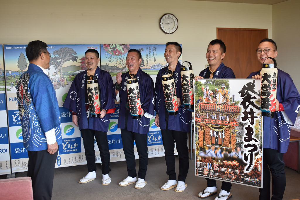 大場市長（左）にポスターを見せる袋井十五町祭典統一委員会のメンバー＝袋井市役所