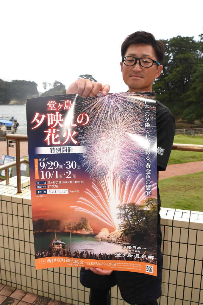 「堂ケ島夕映えの花火」のポスターを見せる職員＝西伊豆町