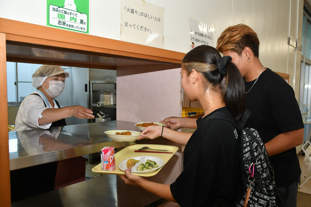 給食の皿を受け取る生徒（右側）＝富士宮市の富士宮東高