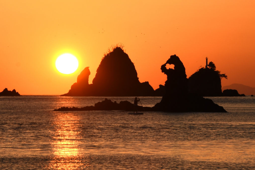 島や岩のシルエットを浮かばせながら海に沈む夕日＝西伊豆町の大田子海岸