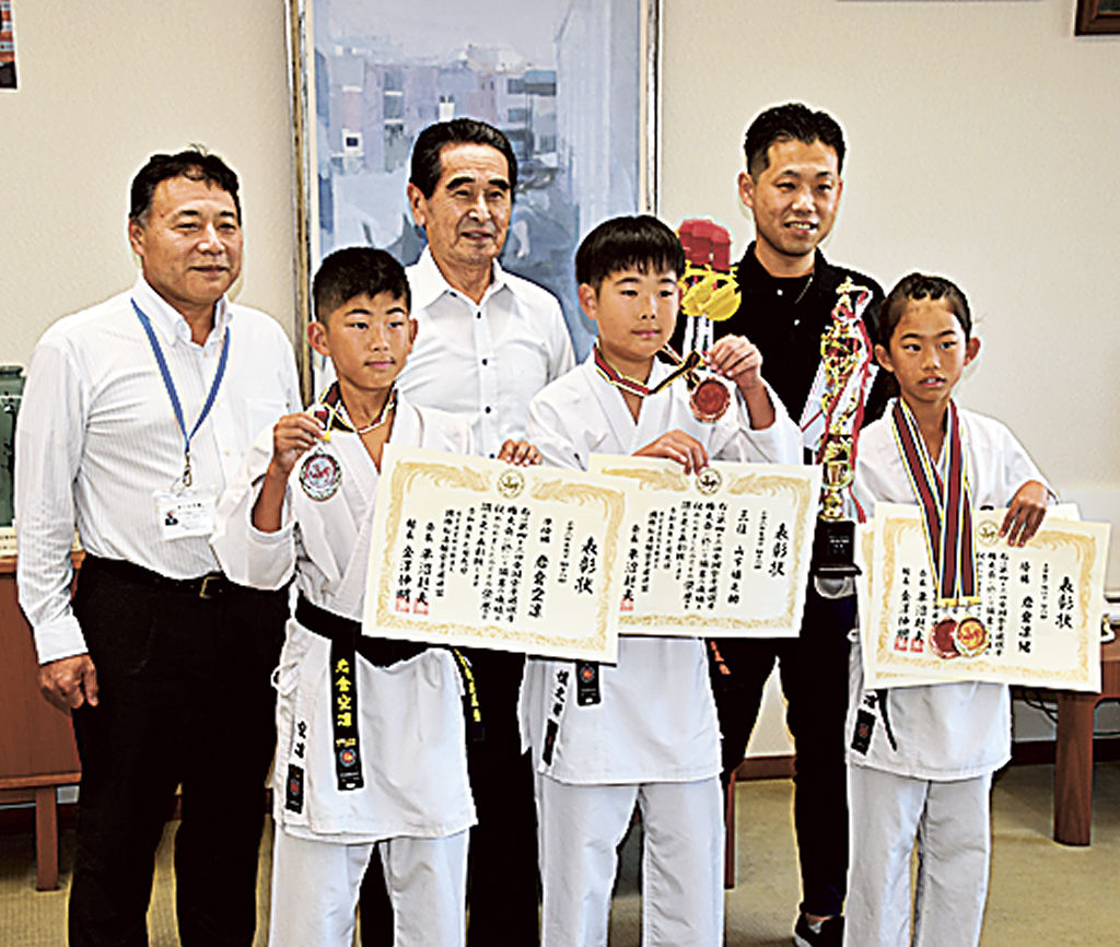 空手の世界大会優勝を報告した岩倉さん（後列右）と全国大会で活躍した小学生ら＝御前崎市役所
