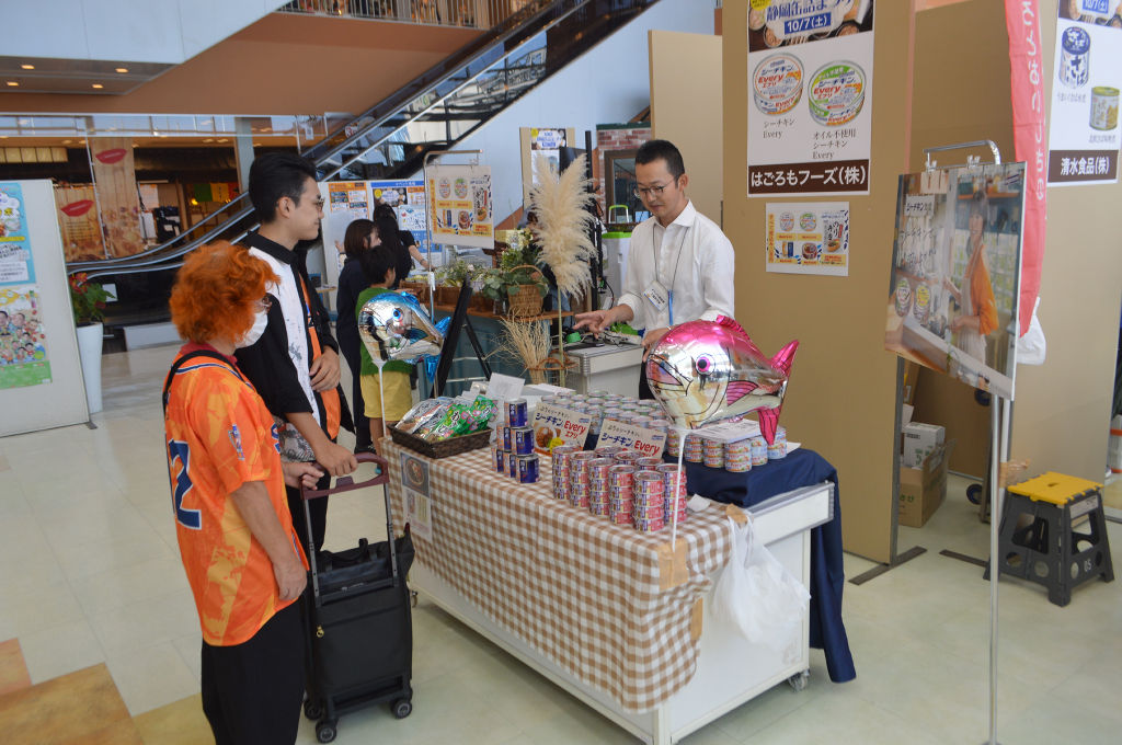 割引価格で提供されている缶詰を品定めする買い物客＝静岡市清水区のエスパルスドリームプラザ