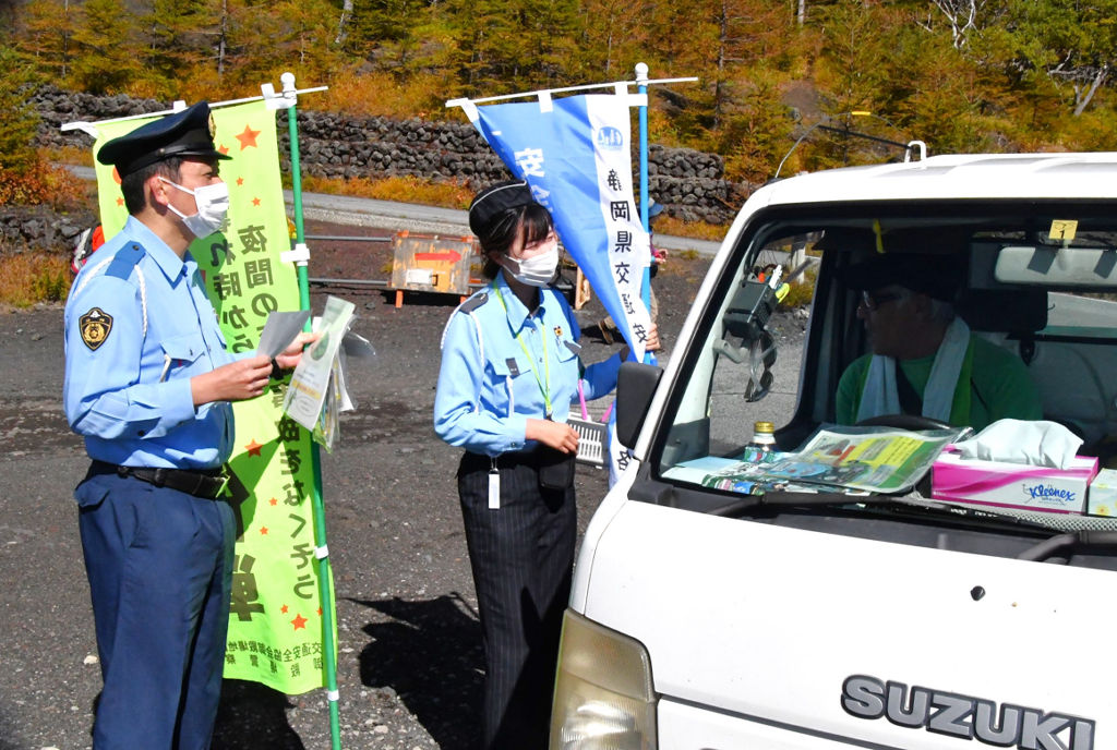 啓発チラシを配布する署員や交通安全指導員＝１３日午前、小山町の富士山須走口５合目
