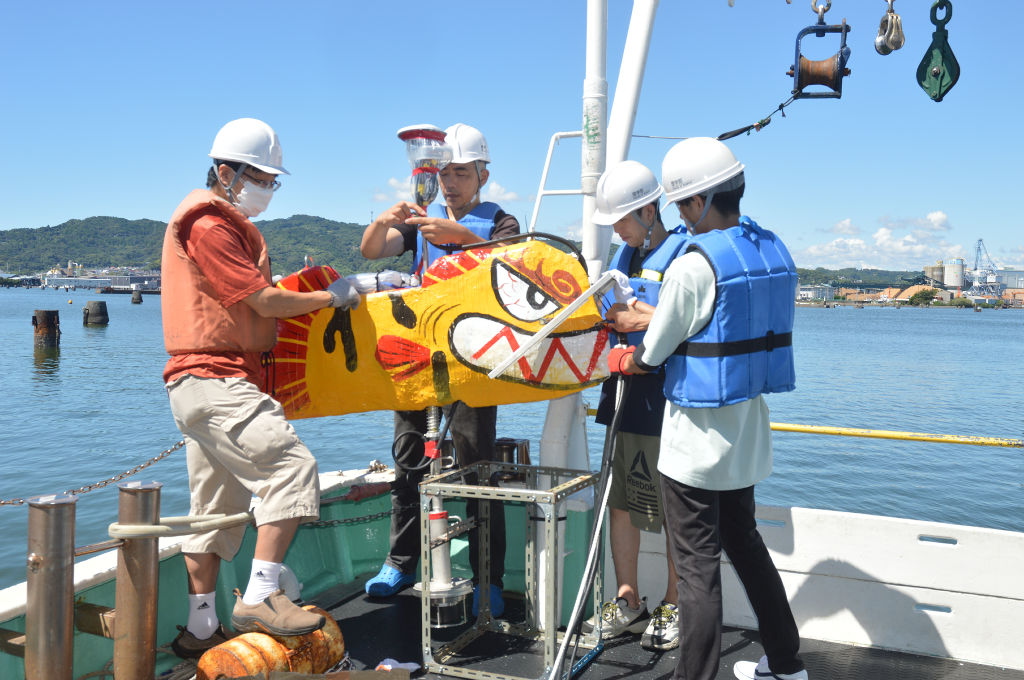 研究グループが開発中の魚型ブイに観測機器を取りつけるメンバー＝８月下旬、静岡市清水区の駿河湾