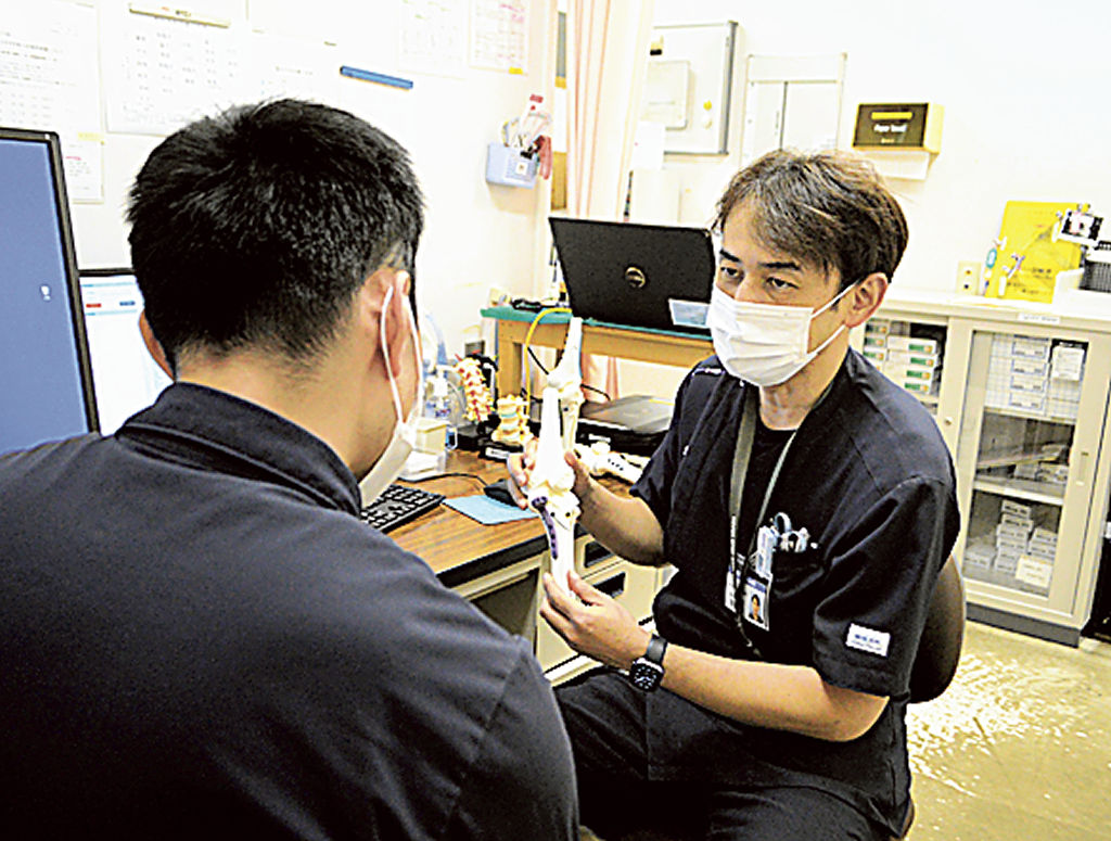 膝のモデルを手に手術について説明する阿部センター長（右）＝菊川市東横地の市立総合病院