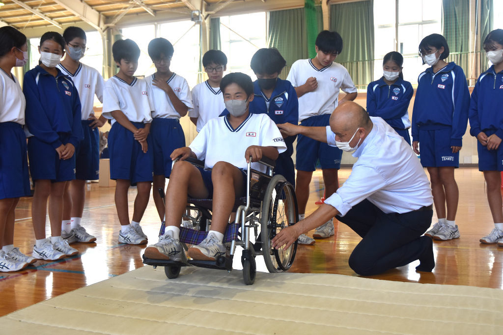 マットを障害物に見立て、車椅子の誘導を学ぶ生徒＝浜松市東区の天竜中