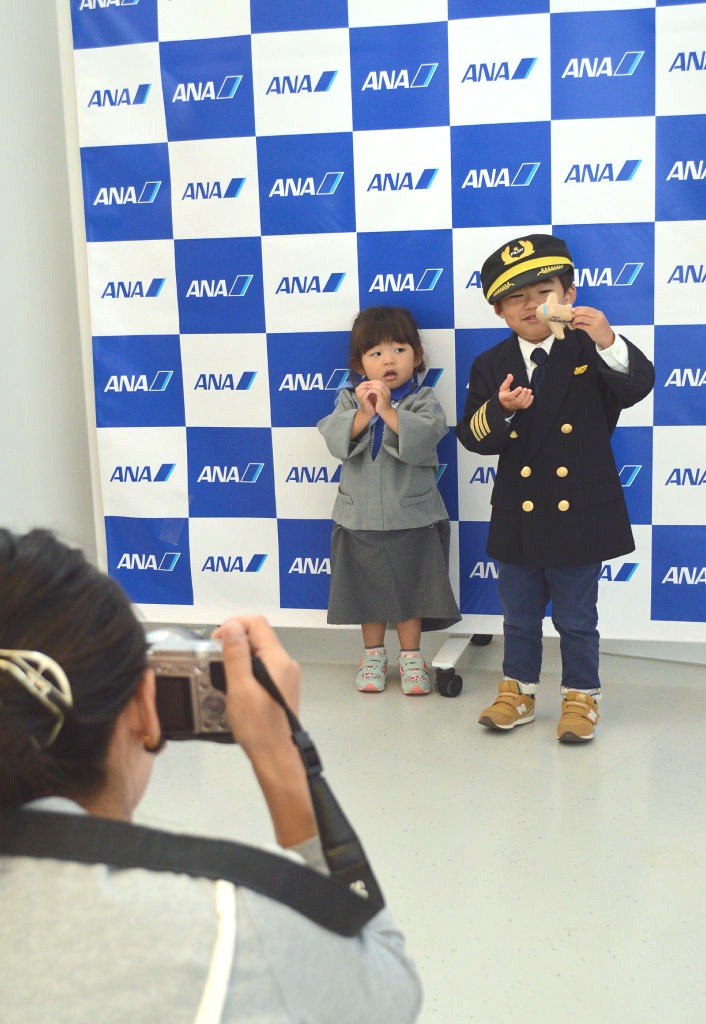 パイロットや客室乗務員の制服を着て写真撮影を楽しむ親子連れ＝静岡空港