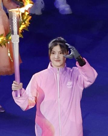 杭州アジアパラ大会の開会式で聖火台に向かうＡＩ搭載の義手を装着したランナー＝２２日、杭州（共同）