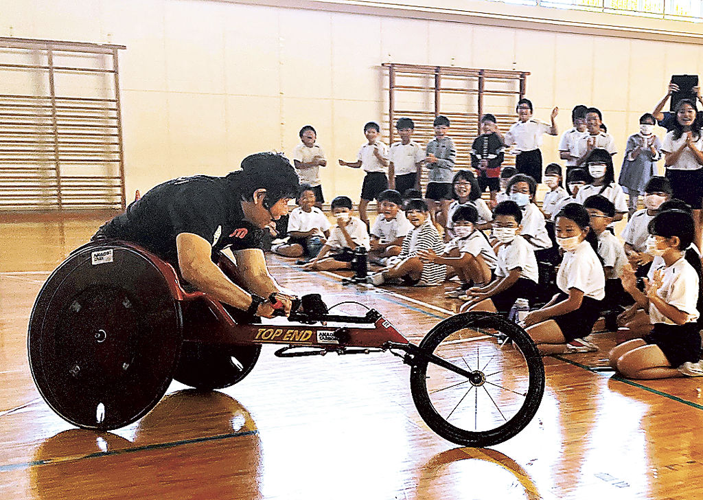 児童の前で陸上競技用車いすを操作する永尾さん（左）＝熱海市立多賀小（日本財団パラスポーツサポートセンター提供）