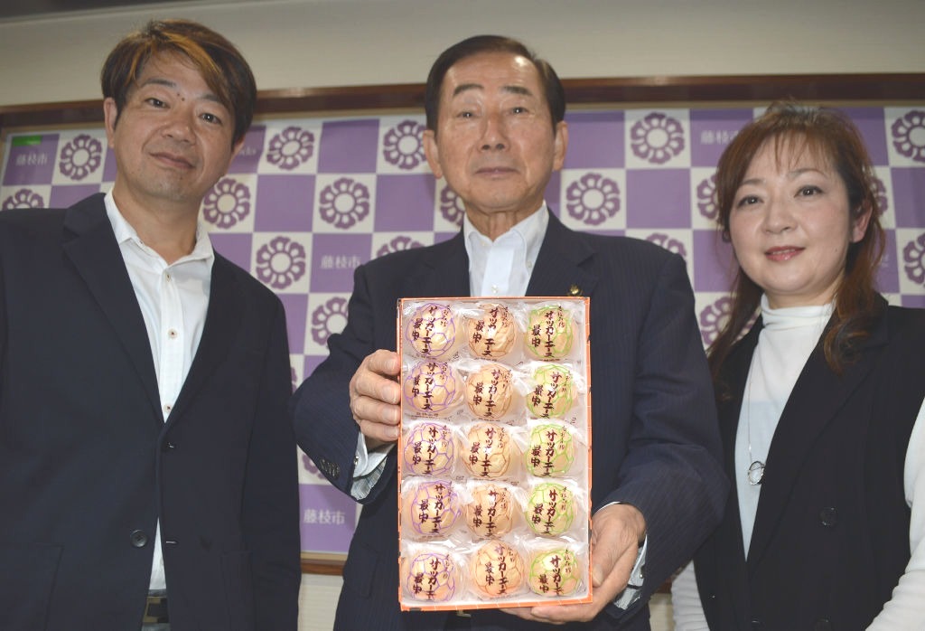 北村藤枝市長（中央）にサッカーエース最中を手渡した山本健太さん（左）と友香さん＝市役所