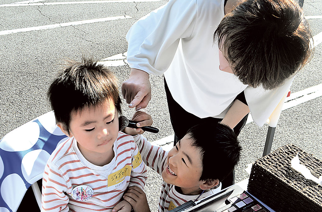 化粧品店の店員になりきってチークを塗る子どもら＝富士市比奈の昭和自動車学校