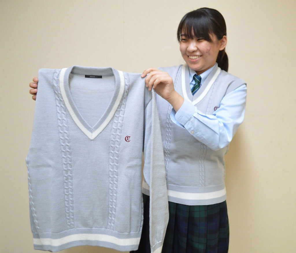 新セーターを着用し紹介するデザイン発案者の一人小山さん＝長泉町の知徳高