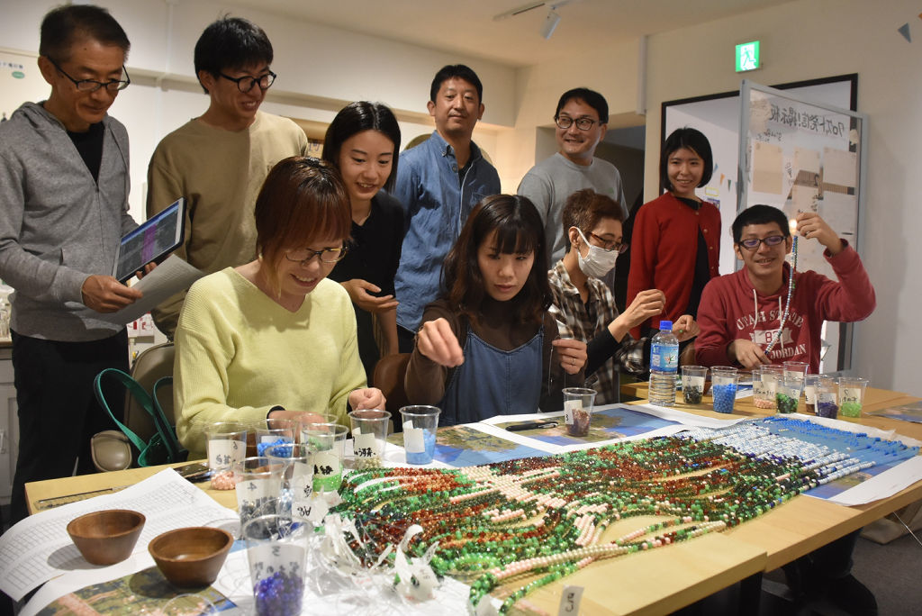 辻さん（左から４人目）の指導を受けながら作品作りに協力する参加者＝１０月初旬、三島市