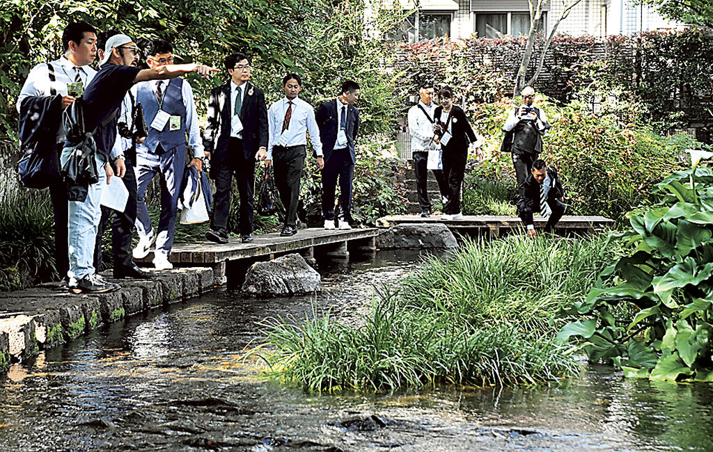 山本副会長（左から２人目）の案内で市街地を散策する参加者＝三島市