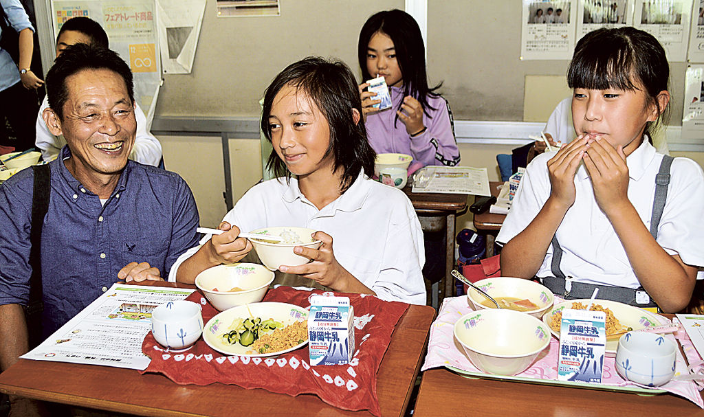 松下副会長（左）の説明を受けながら、有機米と有機茶を味わう児童＝藤枝市立青島小