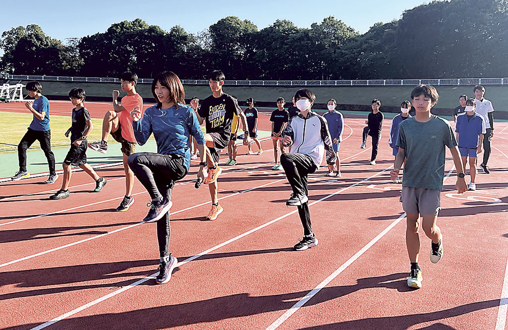 高橋さんから走り方を教わる生徒ら＝富士市の富士総合運動公園陸上競技場