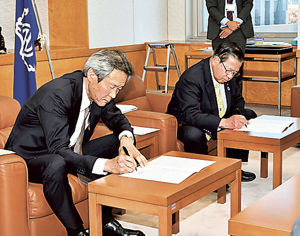 協定書に署名する濱田社長（手前）と須藤市長＝富士宮市役所