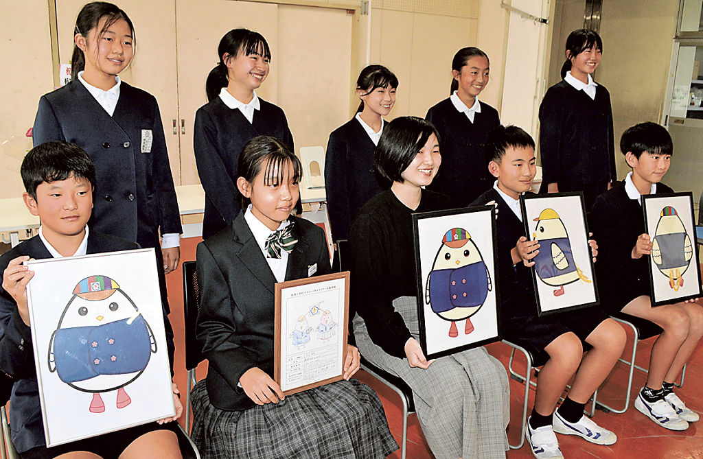 村松さん（前列左から２人目）と三浦さん（同３人目）から「たかすっこ」のデザイン画を受け取った児童＝藤枝市立高洲小