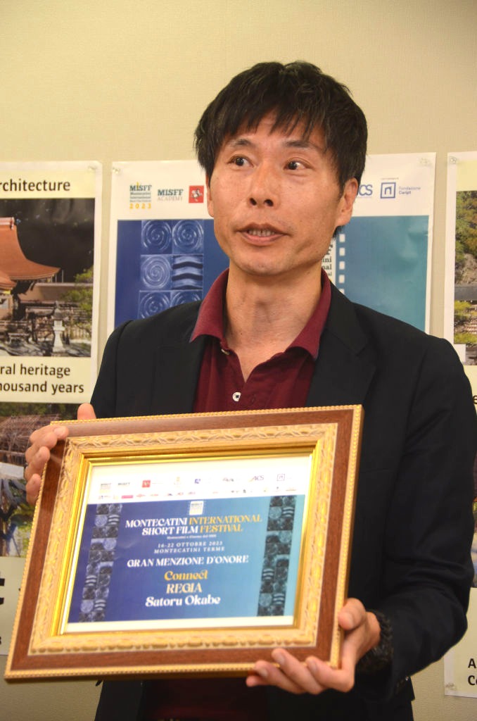 モンテカティーニ国際短編映画祭の表彰状を手に受賞作を説明する岡部さん＝浜松市役所